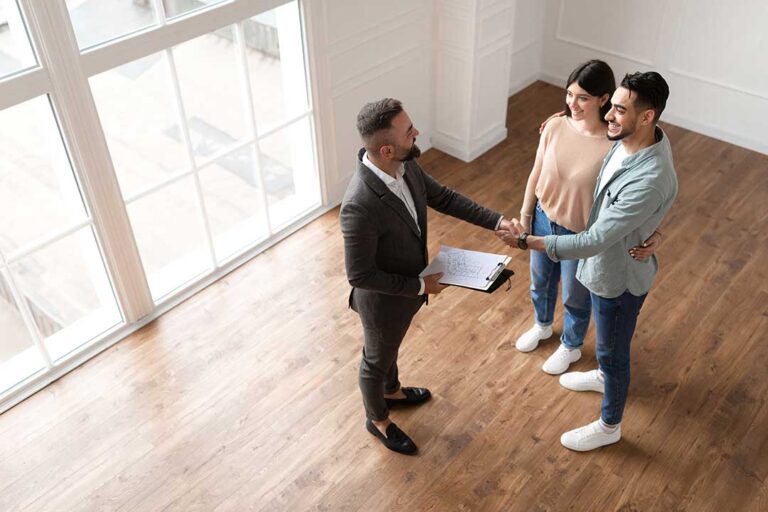 First-time buyers review a home inspection report at a kitchen table with documents and a calculator.